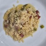 “Creamy risotto with asparagus and crispy pancetta served on a plate”.