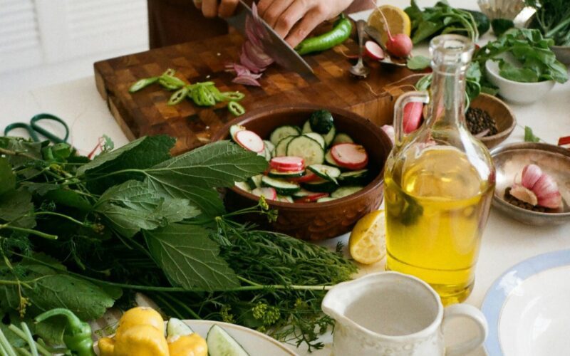 pexels-photo-9986235-9986235 Adult preparing salad with fresh vegetables, knife, and olive oil in kitchen setting. Taste Home Recipes